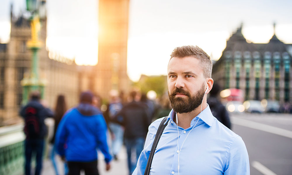 man walking in london near westminster bridge with earphones